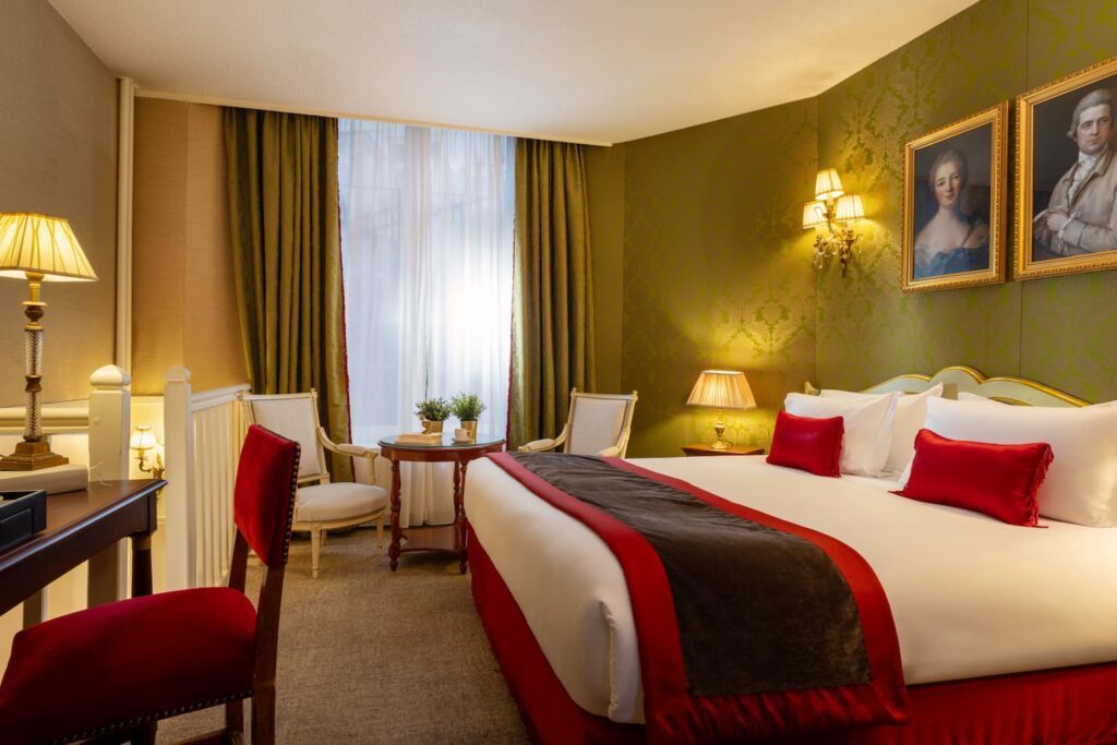 chambre avec lit blanc, coussins rouges, tissu vert et petit coin salon devant une large fenêtre | chambre romantique paris | hotel de seine paris | chambre d'hotel avec baignoire