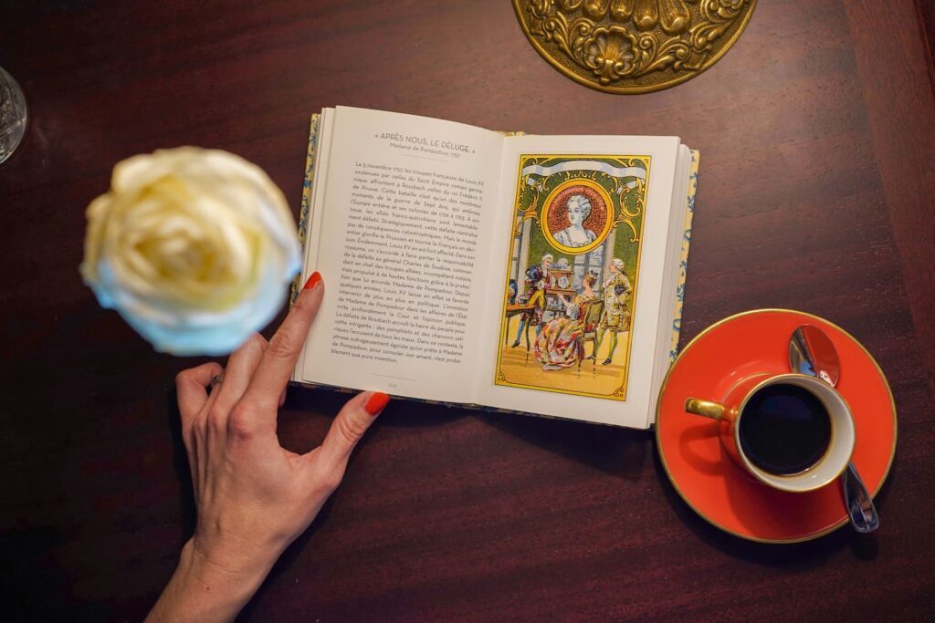 Libro abierto con una página dedicada a la marquesa de Pompadour y una taza de café