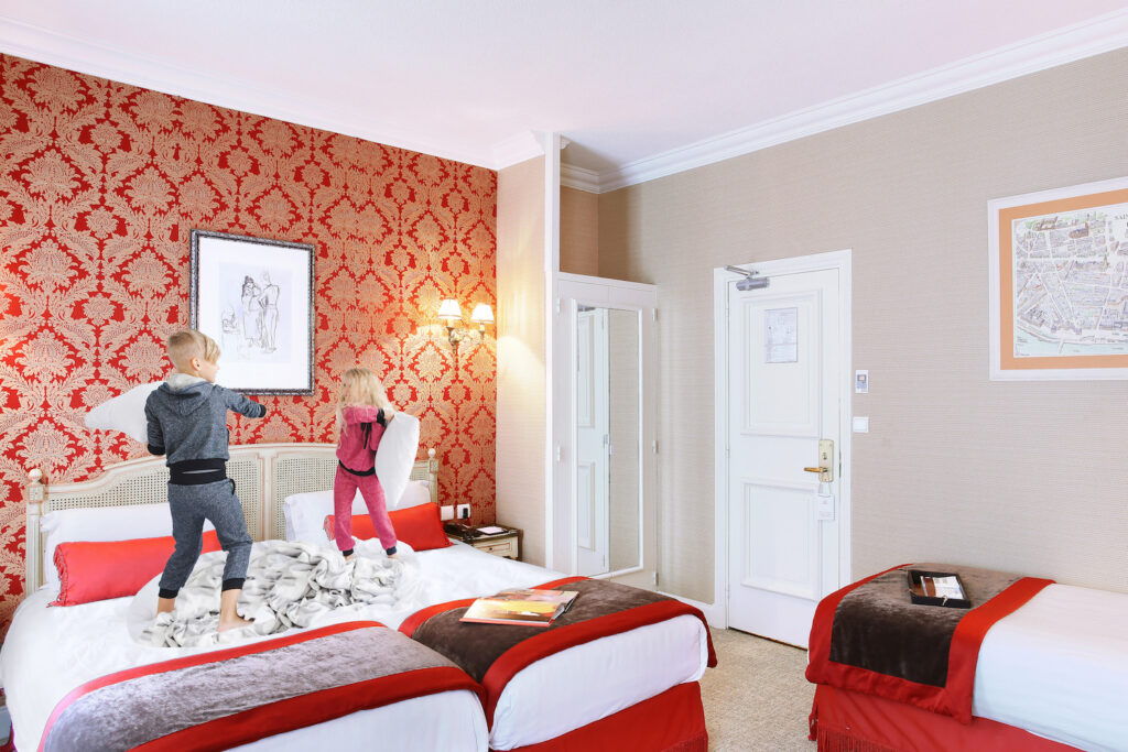 enfants jouant sur le lit à l'hôtel de seine, dans une chambre à trois lits - visiter paris avec des enfants